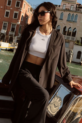Woman wearing Dreamscape Button Down Long Sleeve shirt and high-waist trousers by a canal.