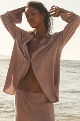 Model wearing Dreamscape Button Down Long Sleeve shirt by the beach, showcasing oversized style and breathable fabric.