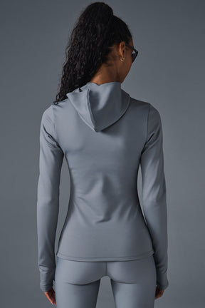 Back view of a woman wearing a gray Airlift Winter Warm Hooded Runner, showcasing its sleek design and built-in hood.