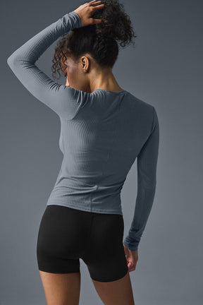 Back view of a woman wearing the Ribbed Sea Coast Long Sleeve shirt paired with black shorts.