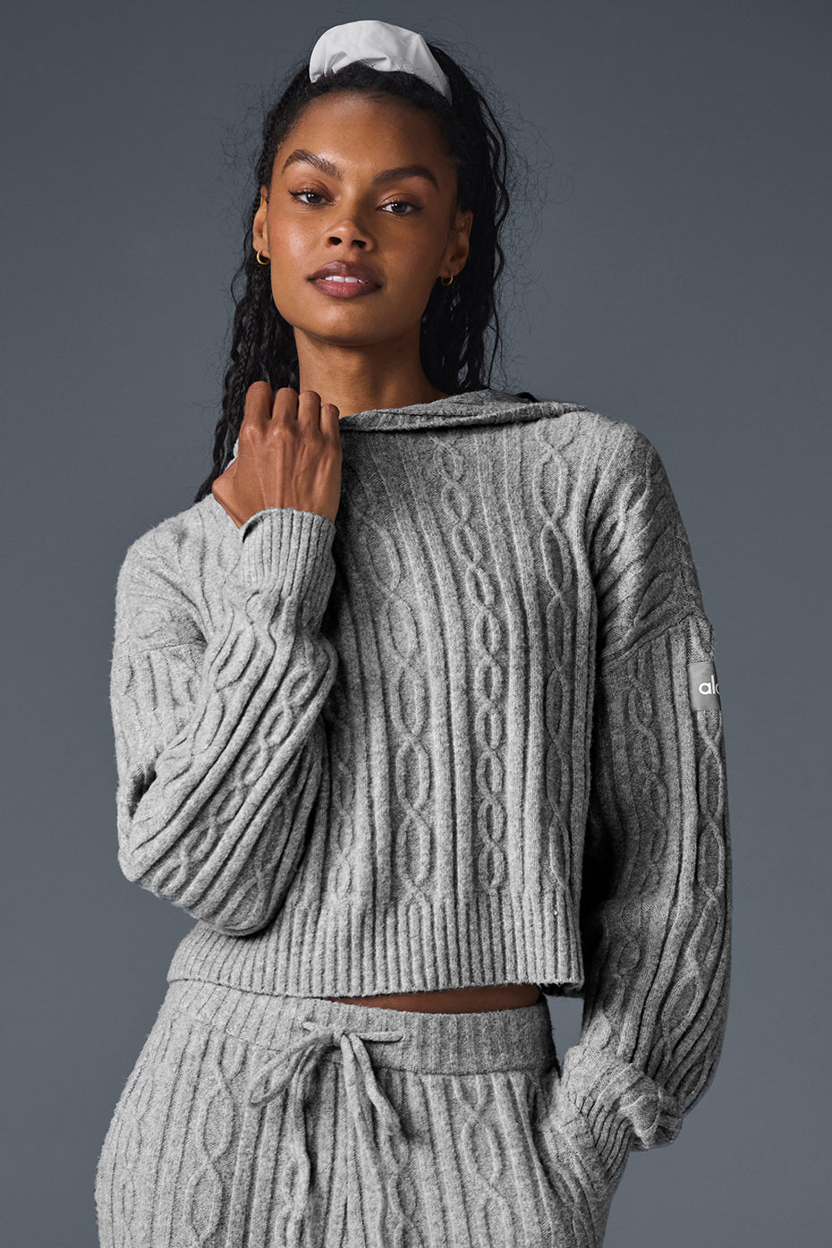 Gray cable knit winter bliss hoodie with relaxed fit and cropped hem, styled with matching pants.