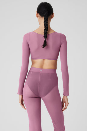 Mesh sheer illusion cropped long sleeve top in pink, featuring a boat neck and rib-grazing design, styled with matching pants.