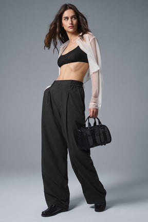 Model wearing a sheer cropped button-up with a black bralette and tailored pants, showcasing a chic outfit.