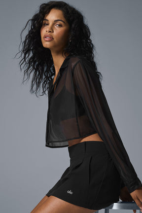 Model showcasing a sheer cropped button-up shirt paired with a skirt, highlighting chic styling options.