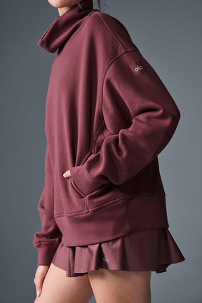 Hazy mock neck pullover in burgundy worn with a matching skirt, showcasing an oversized fit and cozy design.