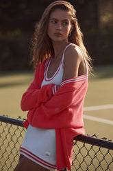 Model wearing Tennis Club sweater knit cardigan over a sporty ensemble on a tennis court, showcasing style and comfort.