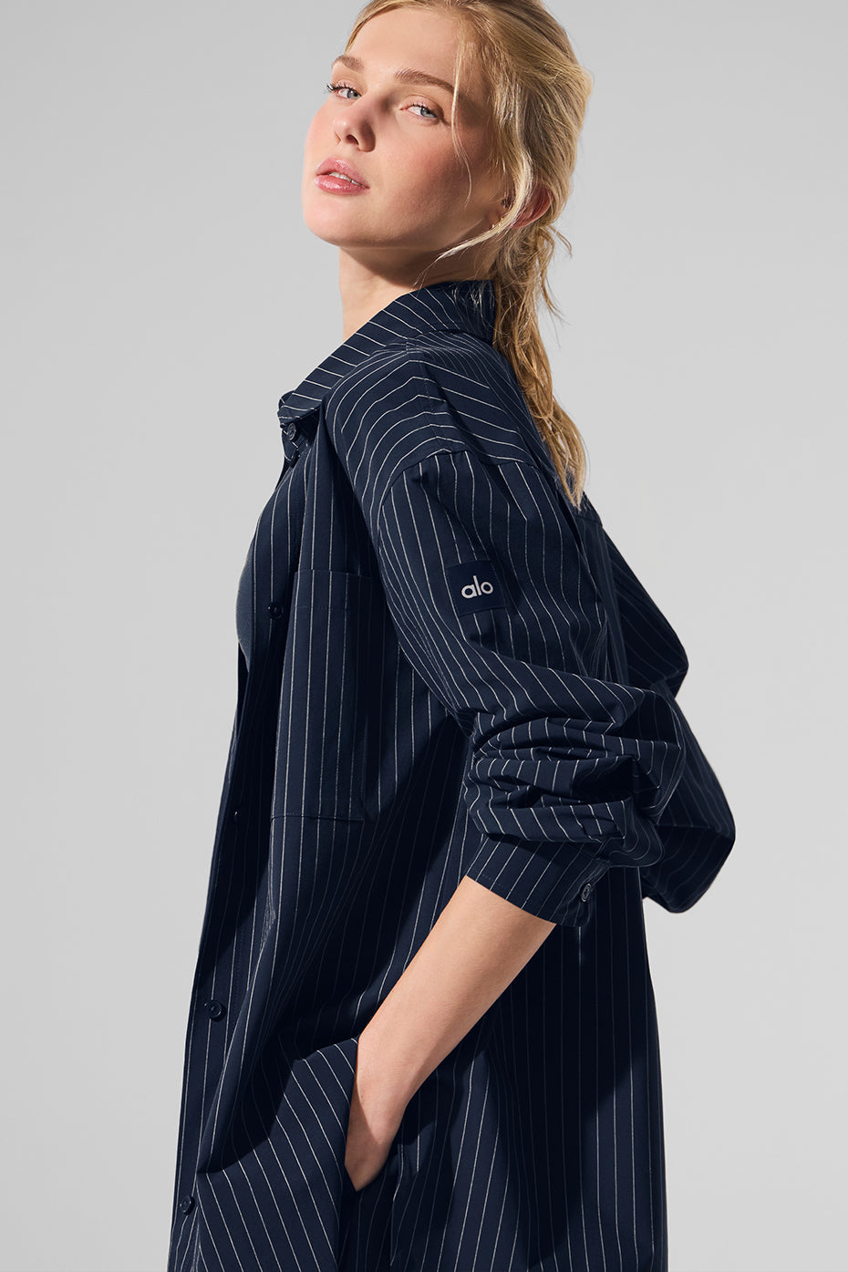 Model wearing a navy pinstripe button down long sleeve shirt with a classic collar and oversized fit.