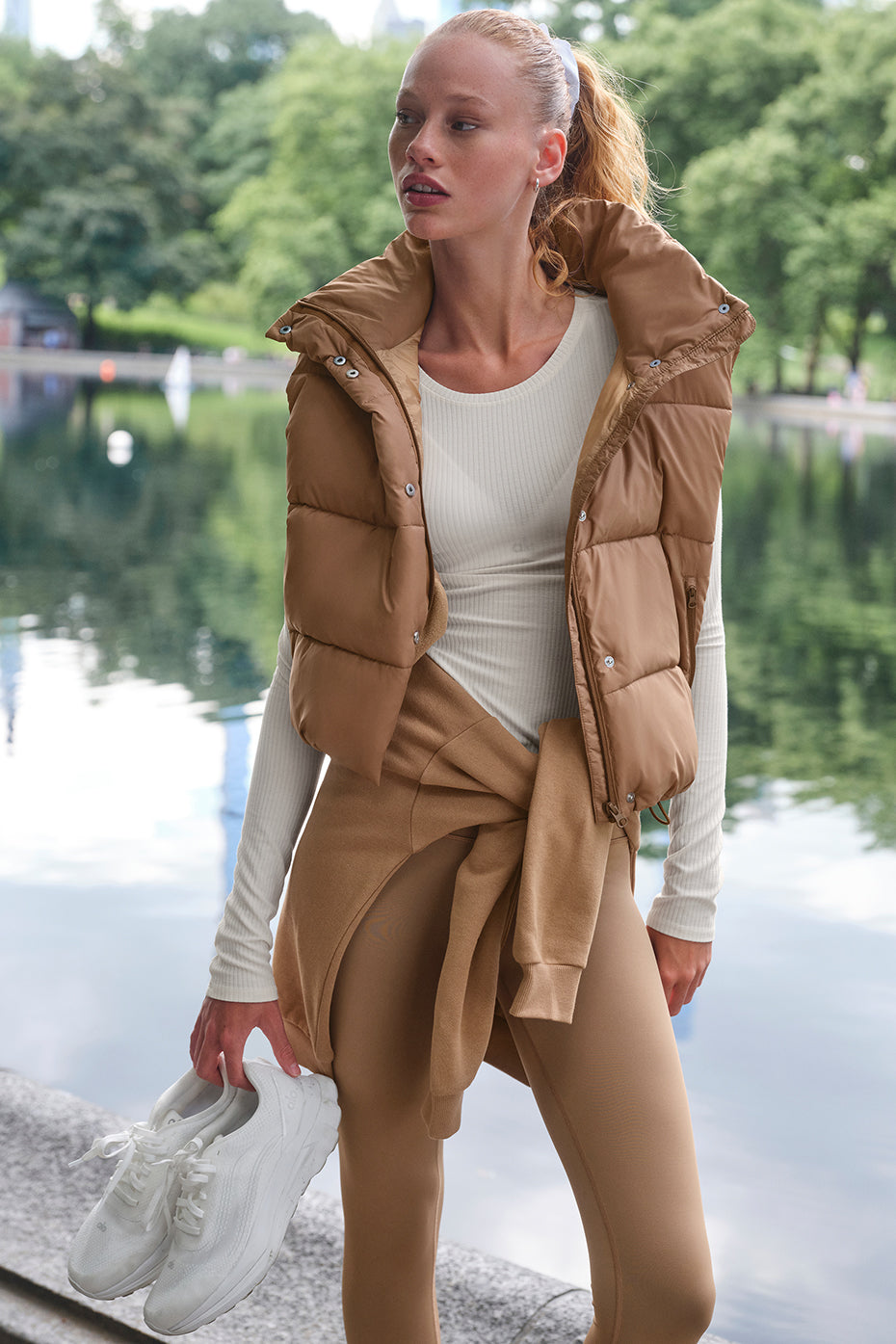 Woman in cozy-luxe Gold Rush Puffer Vest with cinched design and hooded collar, styled for seasonal looks.