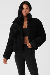 Woman wearing a black Sherpa Snow Angel Puffer jacket, showcasing its cozy design and tall collar.