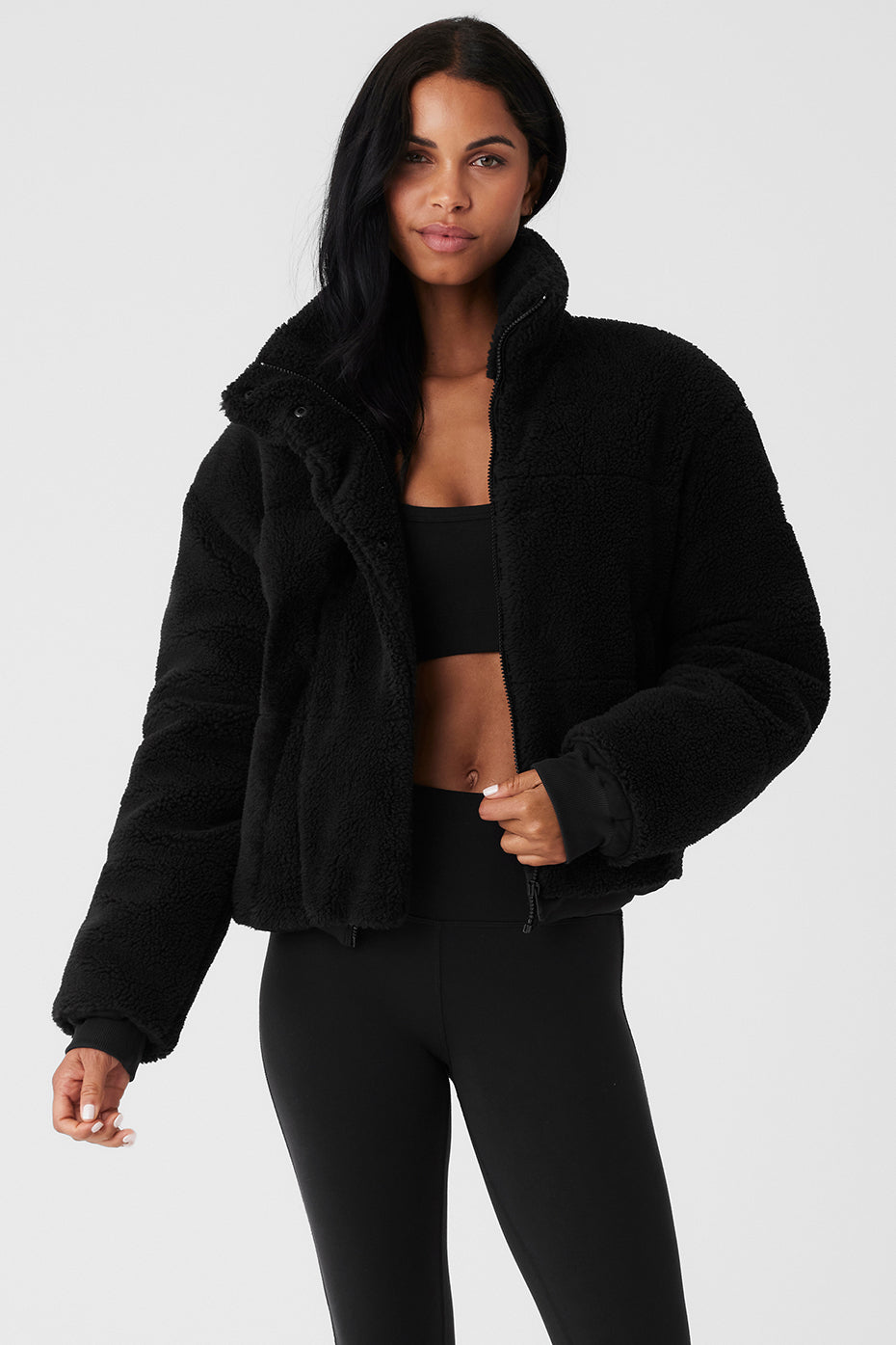 Woman wearing a black Sherpa Snow Angel Puffer jacket, showcasing its cozy design and tall collar.