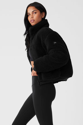 Sherpa Snow Angel Puffer in black, designed for warmth with tall collar and deep zippered pockets, perfect for layering.
