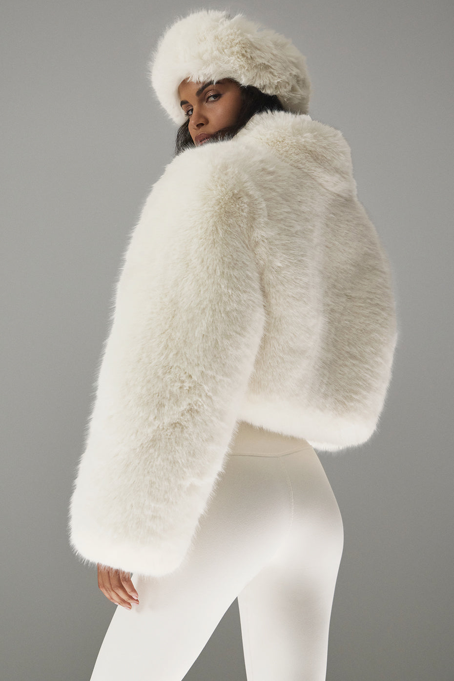 Opulent faux fur cropped jacket with a stand collar and boxy shape, styled with matching hat, showcasing chic elegance.