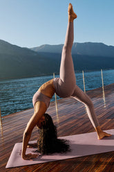Woman practicing yoga in Alosoft High-Waist 7/8 Highlight Legging by the water in a serene outdoor setting.