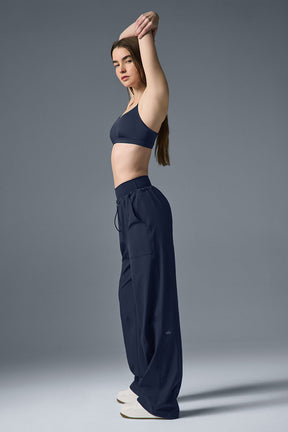 Woman stretching in navy Megastar Cargo Pants and matching crop bra showcasing modern Y2K style and adjustable fit.