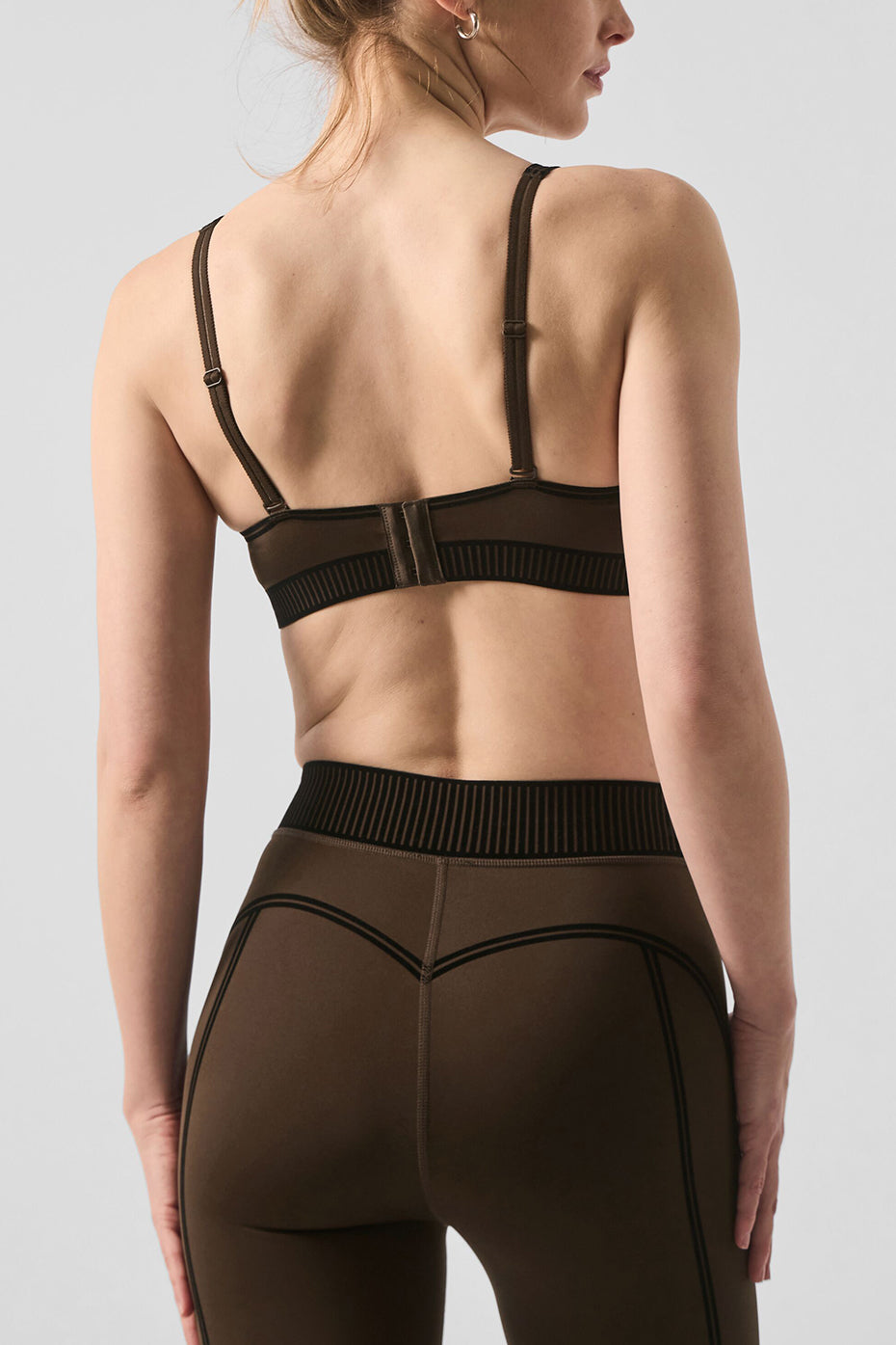 Model showcasing the back of the Airlift High-Waist 7/8 Line Up Legging and matching bra in brown.