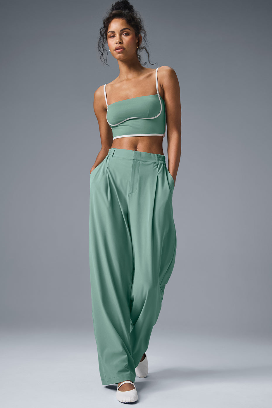 Model wearing high-waist pursuit trousers in green, featuring a relaxed wide-leg fit and tailored details.
