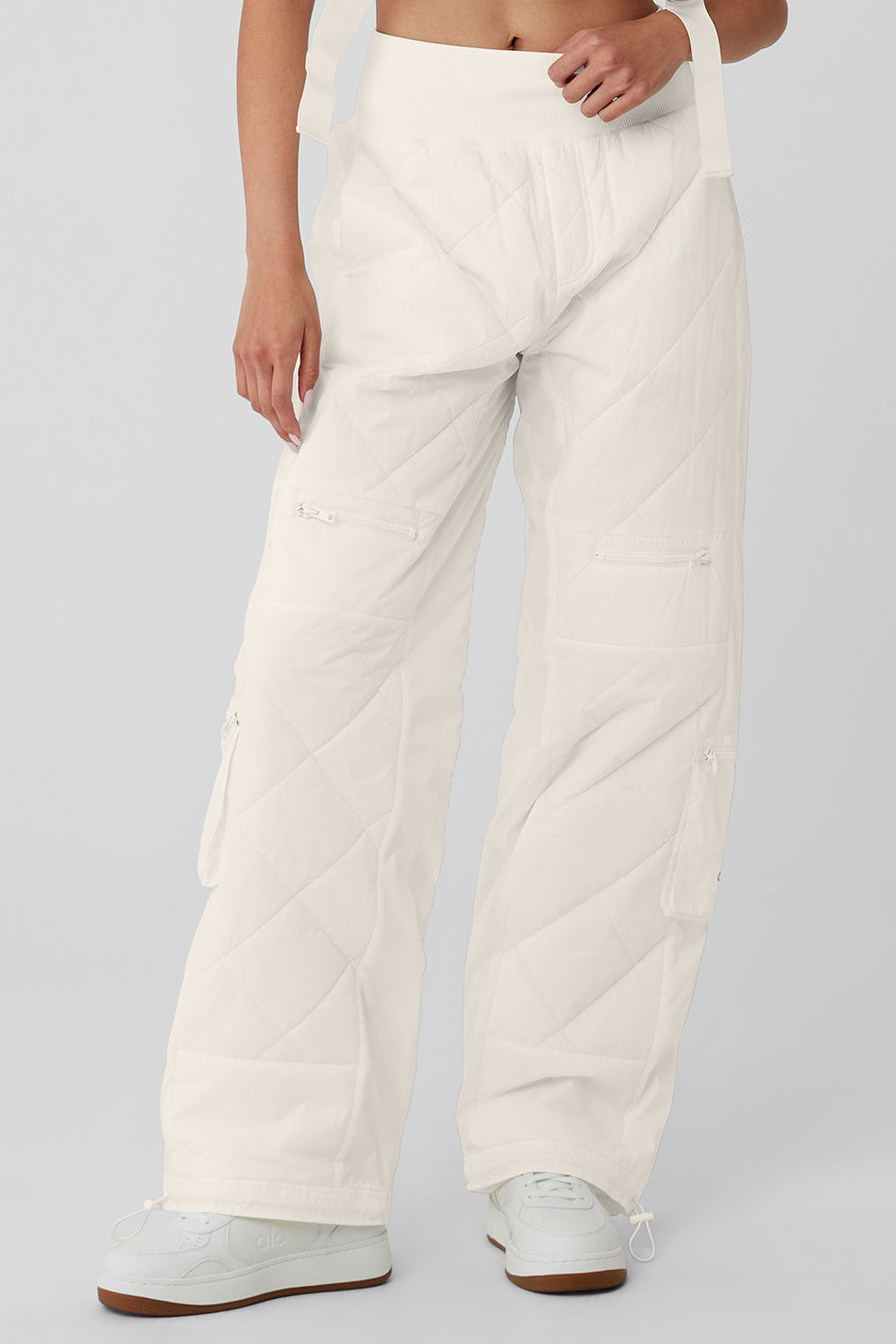 High-waist Snowrider puffer pants in white with quilted finish, wide waistband, and multiple zipped pockets.