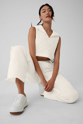 Model wearing High-Waist Snowrider Puffer Pant with quilted finish and hooded crop top in white.