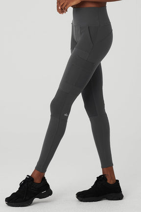 High-waist cargo legging in dark gray, featuring multiple pockets and sculpting fabric, ideal for studio and street wear.
