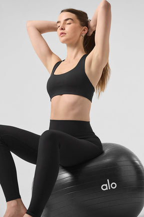 Model wearing High-Waist Solid Vapor Legging and black sports bra, sitting on exercise ball, showcasing sleek design and fit.
