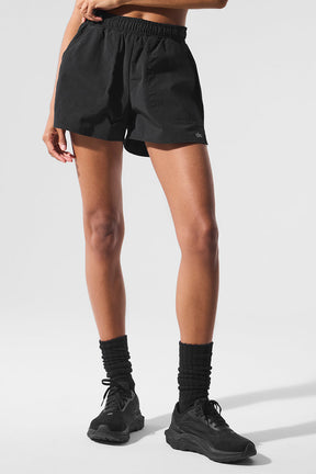 Model wearing black Alumni Short, featuring high-waist design and side pockets for essentials, perfect for hiking and exploring.