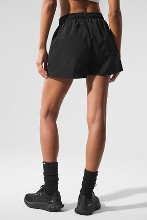 Model wearing black Alumni Shorts showcasing high-waist design, side pockets and lightweight fabric, ideal for hiking and exploring.