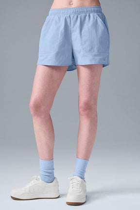 High-waist lightweight Alumni Short in light blue, designed for comfort with pockets for essentials and paired with sporty shoes.