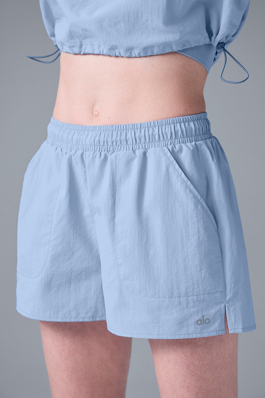 Alumni Short in light blue with high-waist design and side slit pockets for hiking and outdoor activities.