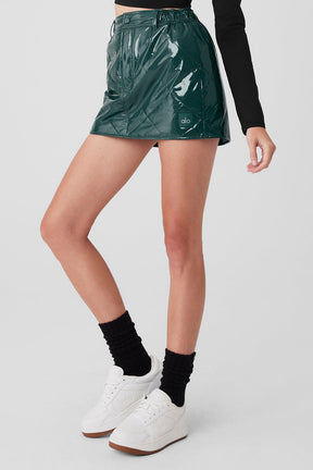 Model wearing a high-shine green puffer mini skirt with quilted finish, styled with white sneakers and black socks.