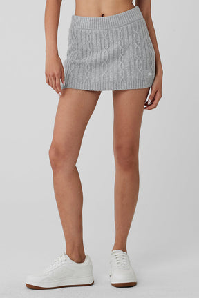 Cable knit mini skirt in gray with elastic waistband, styled with casual white sneakers for a cozy winter look.