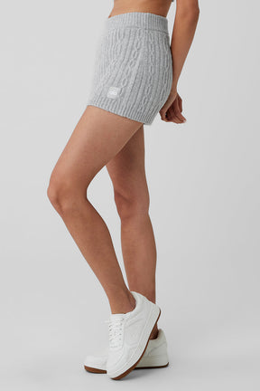 Cable knit winter mini skirt in light gray with elastic waistband and cozy fit, paired with white sneakers.