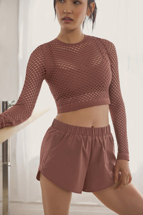 Model wearing sporty Playmaker Dolphin Shorts with a cropped mesh top, showcasing stylish athleticwear.