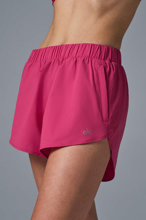 Playmaker Dolphin Short in vibrant pink showcasing elastic waistband and zippered side pockets for style and functionality.