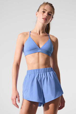 Model wearing Playmaker Dolphin Shorts with a stylish blue sports bra, showcasing sporty and chic activewear.