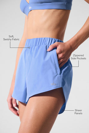 Playmaker Dolphin Short in light blue showcasing soft swishy fabric, zippered side pockets, and sheer panels.