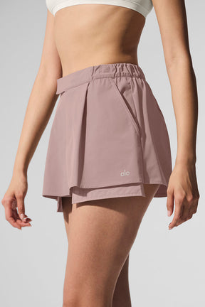 Flip It Mini Skort in dusty rose featuring elastic waistband and ALO logo for versatile comfort and style