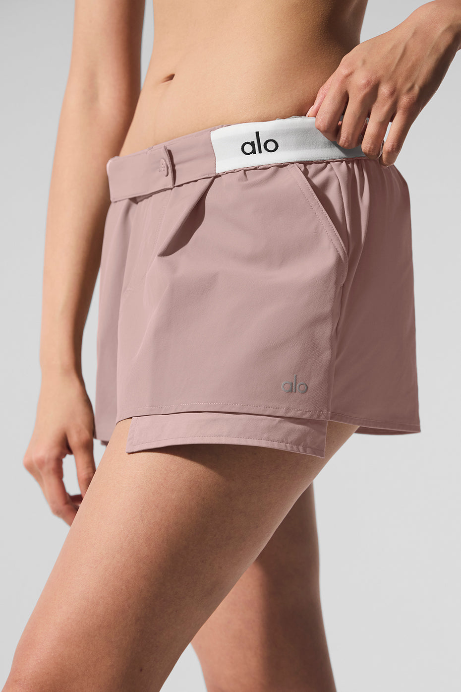 Flip It Mini Skort in soft pink featuring elastic waistband and ALO logo for style and comfort.