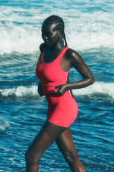 Model wearing 3" ALO Softsculpt High-Waist Precision Short in pink, showcasing a seamless design by the ocean.