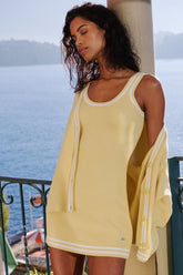 Chic Tennis Club Sweater Knit Dress in yellow with scoop neck and striped trim, styled near a scenic waterfront.