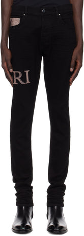 AMIRI black snake logo jeans with skinny-fit, button-fly, and distressed detailing, featuring leather logo appliqué.