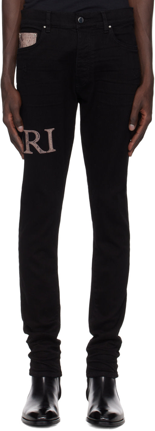 AMIRI black snake logo jeans with skinny-fit, button-fly, and distressed detailing, featuring leather logo appliqué.
