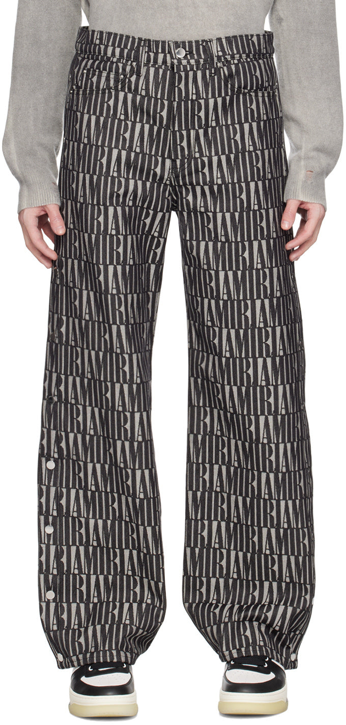AMIRI black snap off jeans in jacquard logo pattern, featuring button-fly and five-pocket styling.
